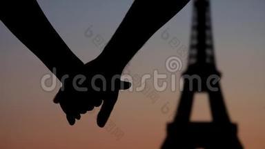 <strong>年</strong>轻的情侣<strong>携手</strong>来到巴黎埃菲尔铁塔前，夕阳下的剪影